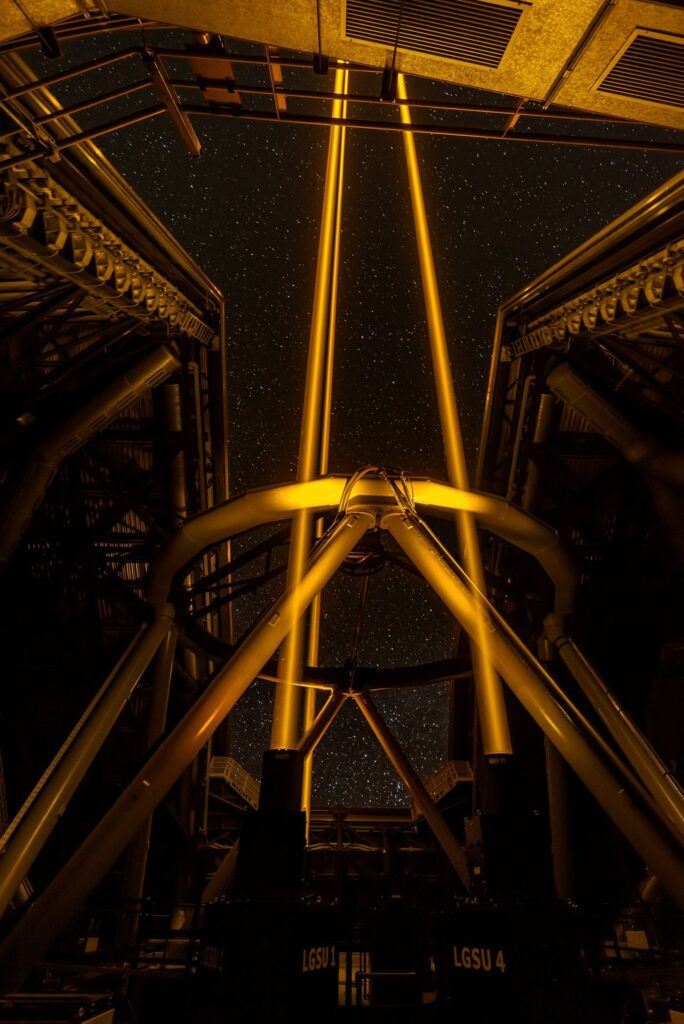 telescope silhouetted under a star-filled night sky