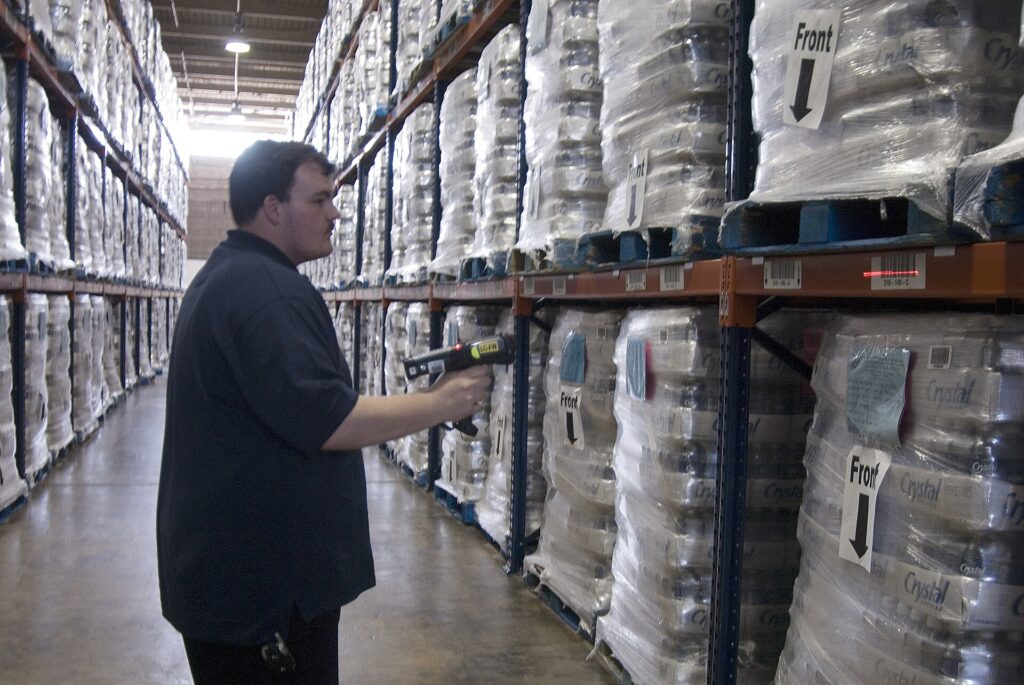 Warehouse Robots Are Everywhere. The Jobs Did Not Vanish — They Moved A worker among tall shelves in a large distribution warehouse