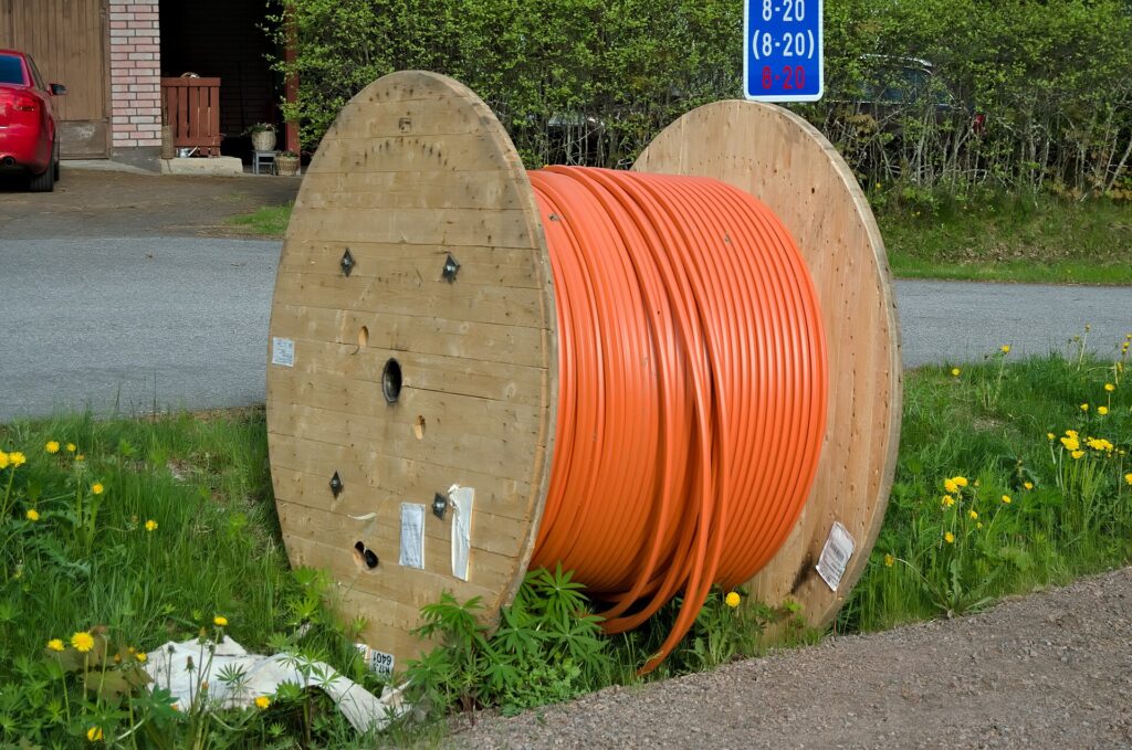 A large reel of orange optical fibre cable ready for network installation